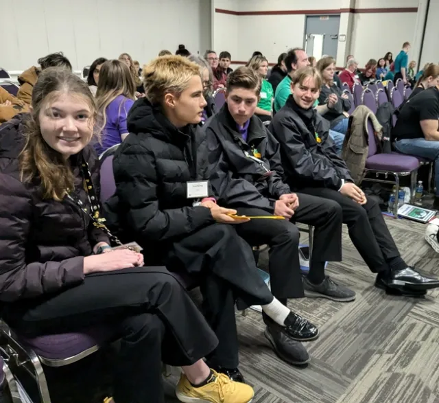 4 youth sitting in the front row of chairs.