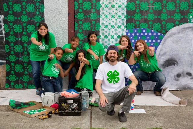 Adult posing with youth in front of wall they cleaned up