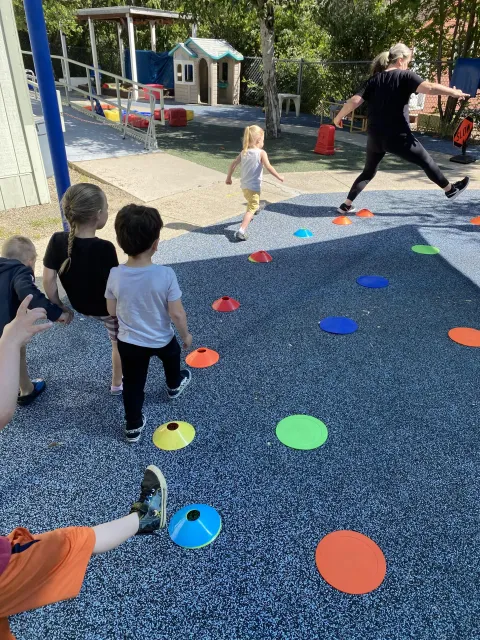 Educator leads young children around a yard as part of a "parading around" activity