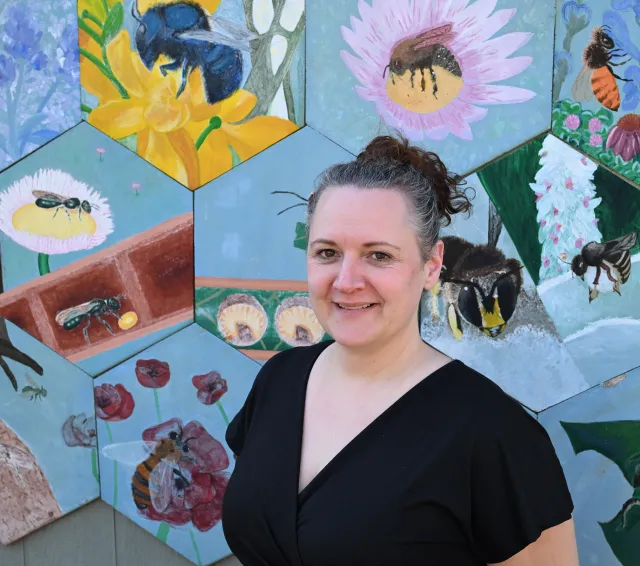 Elina Nino by a wall of bees at the UC Davis Bee Haven