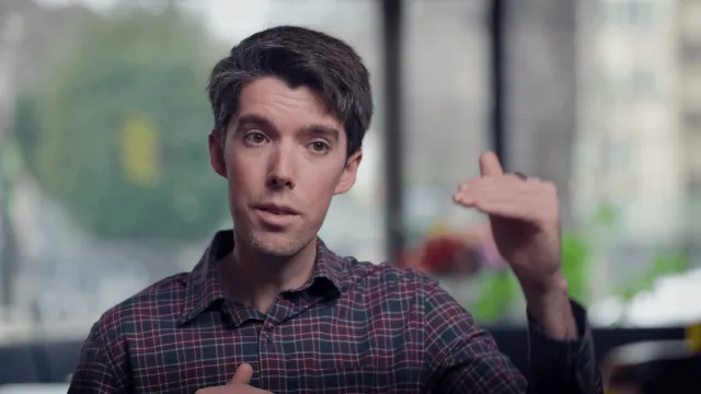 Daniel Swain, wearing a plaid shirt, gestures with his left hand