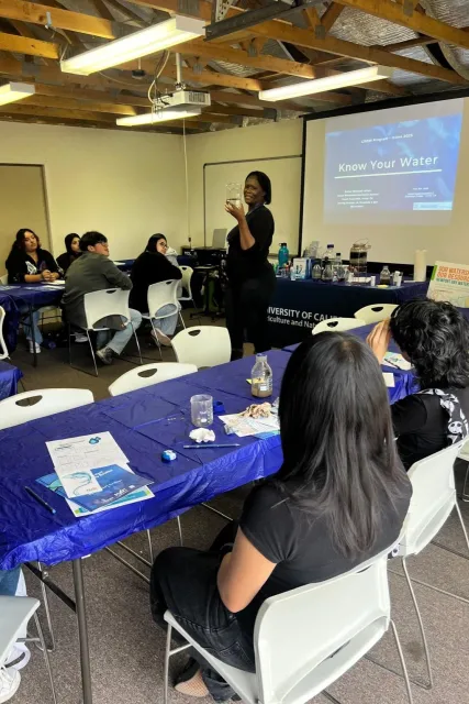 Esther Lofton demonstrates water filtration to students in a classroom