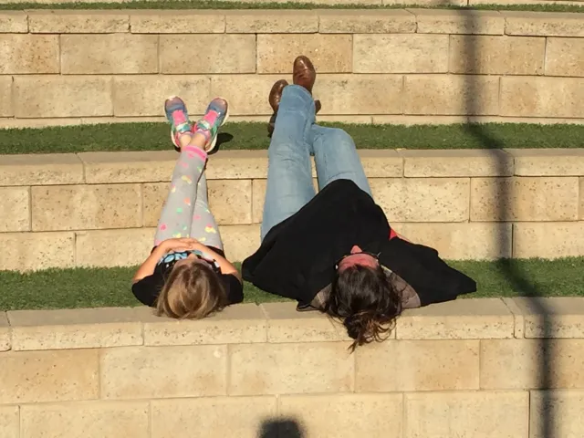 youth and adult laying side by side on their backs on a tiered platform