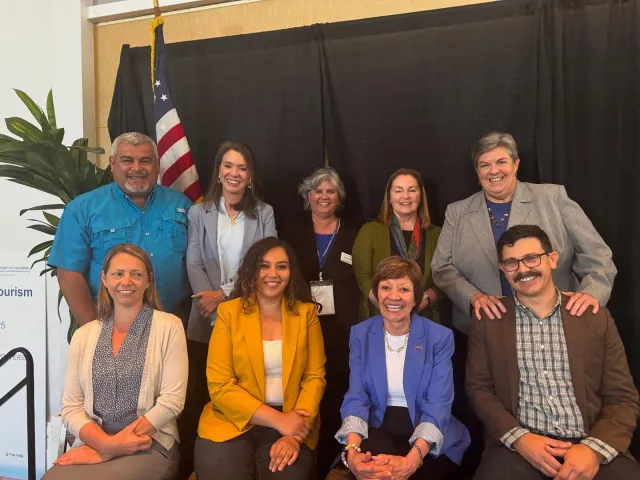 Nine people pose for a group photo, four sitting, five standing