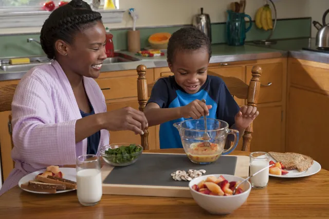 Young child prepares a snack while being supervised