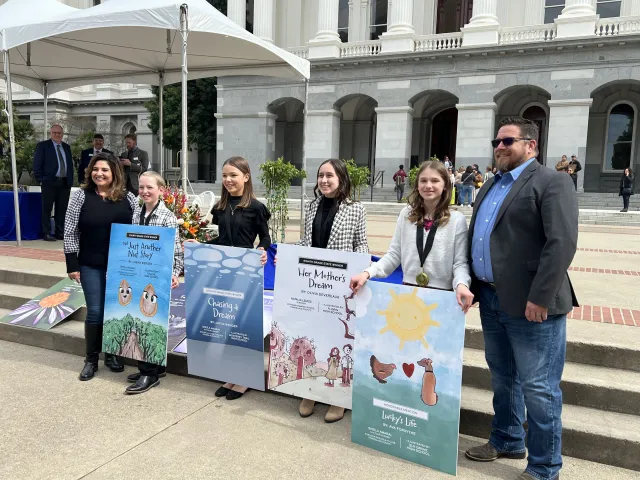 State Senator and State Assemblyman flanking 4 youth authors with their story illustrations