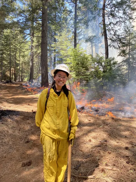 Katie Low stands by a prescribed fire in a forest setting