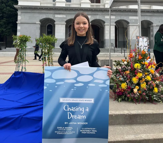Jayna holding her poster of one of the illustrations from "Chasing a Dream"