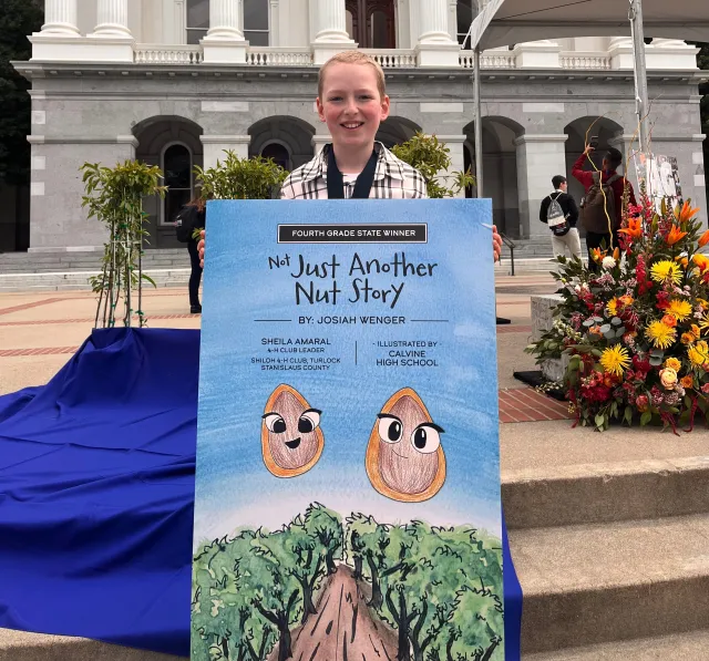 Josiah holding a poster of one of the illustrations for "Not Just Another Nut Story".