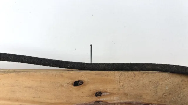 A finishing nail hammered through soaker tubing and a piece of scrap wood.