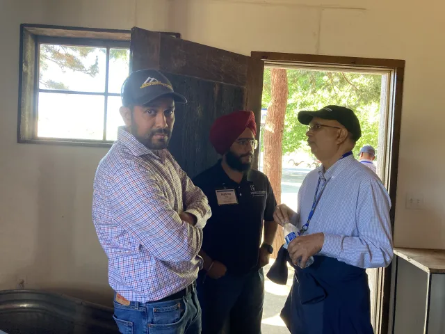 Three men converse next to open door and window
