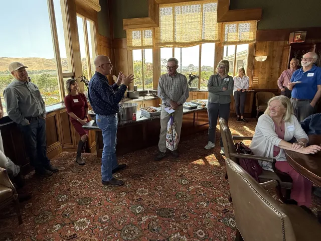 People smile as they celebrate Steve Fennimore in a beautiful room with an expansive view of hills