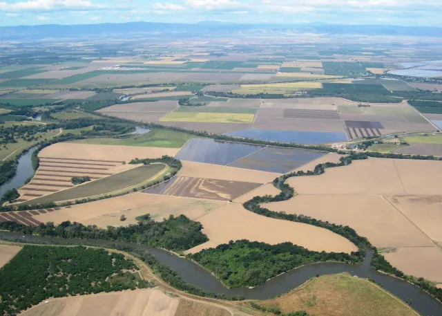 Ag fields between a winding river and mountains in the distance