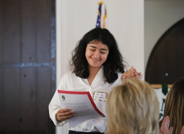 A young woman clasps someone's hand in a high five.