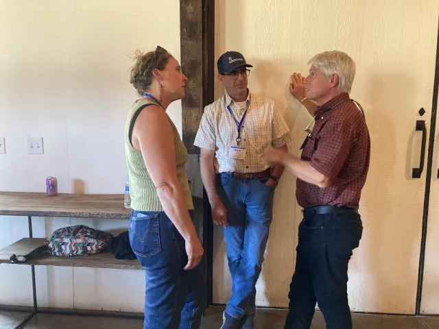 A woman talks with 2 men