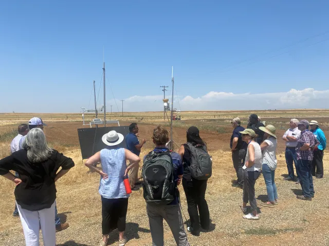 People stand around a weather station in a field