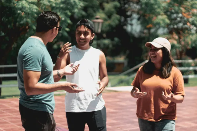 Three people speaking outside in a group