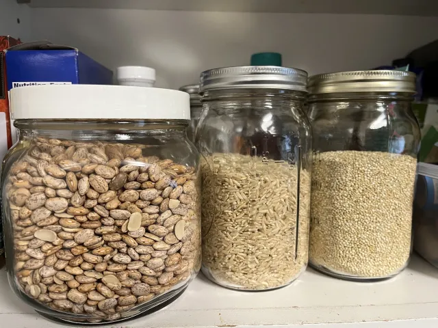 Clear, sealed glass jars that contain beans, rice, and other dried food.