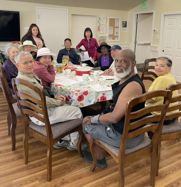 Twelve people of mixed races sit around a dining table