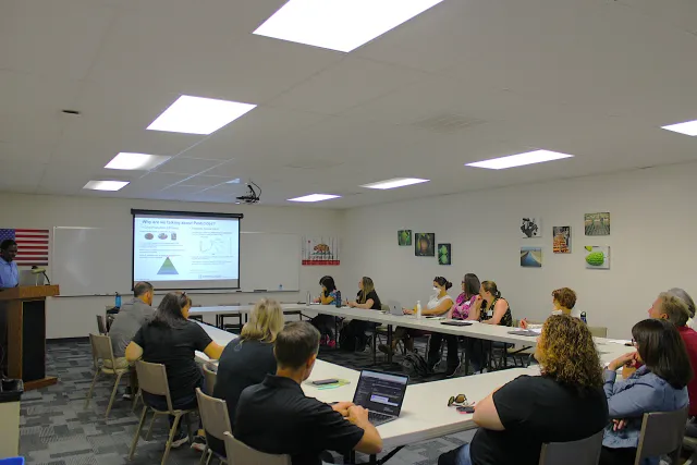 People around table looking at a screen.