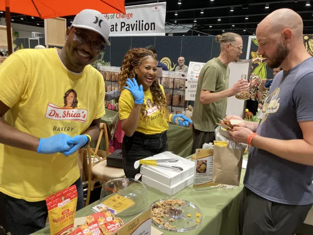 Man and woman smile as they hand out cookie samples