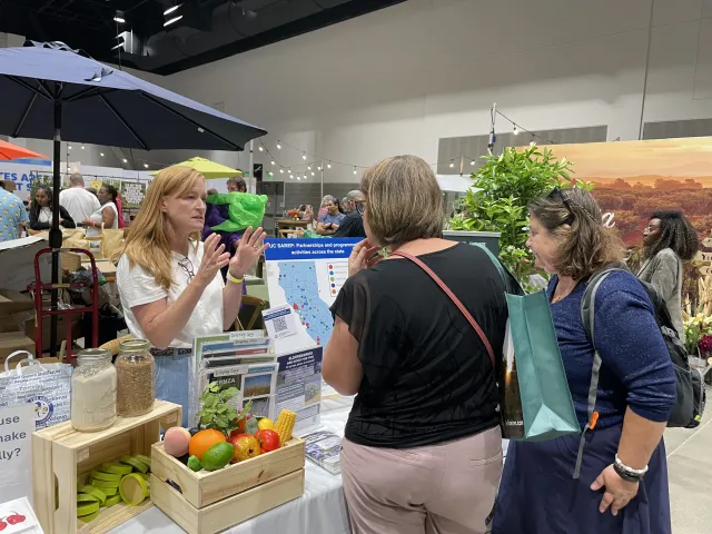 Kristen speaks to 2 women at the SAREP booth