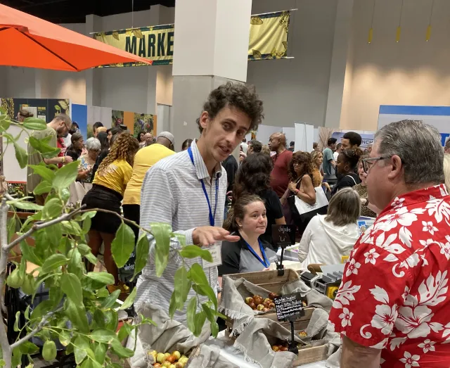 Yonatan gestures toward a jujube tree as he speaks to a man