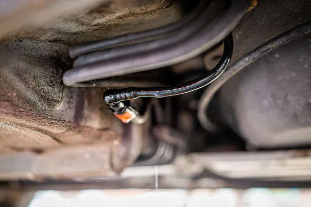 Black and red tubes underneath a car with chew marks from a rodent.