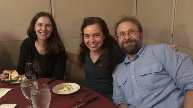 Three people sit at round dining table
