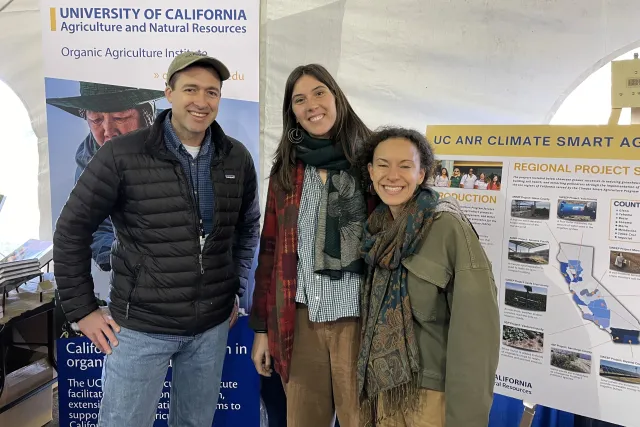 Houston Wilson at left stands with Organic Agriculture Institute staff at their booth at EcoFarm conference
