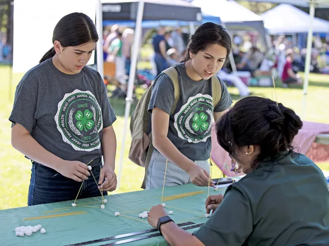 4-H Adult Volunteer demonstrating a project to two youth members