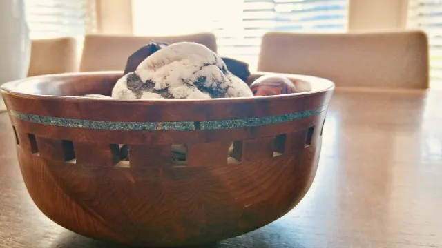 Fine wood bowl with turquoise stones inset in a row all the way around the bowl above a row of square cutouts 