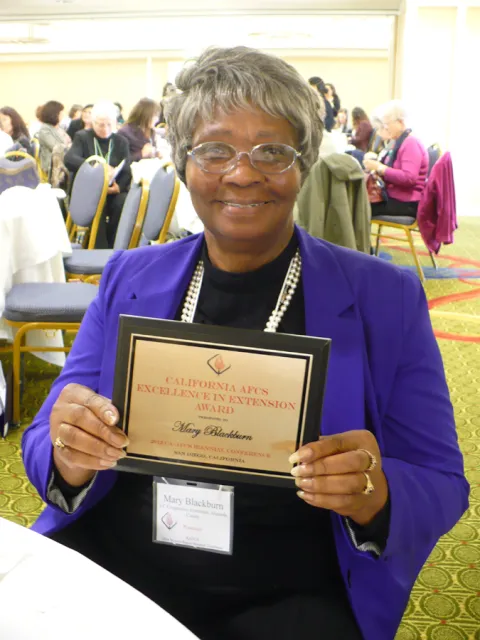 Mary Blackburn holds an American Association of Family and Consumer Sciences Extension Excellence Award plaque in 2012