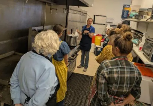 A group of adults in a commercial kitchen watching food preservation