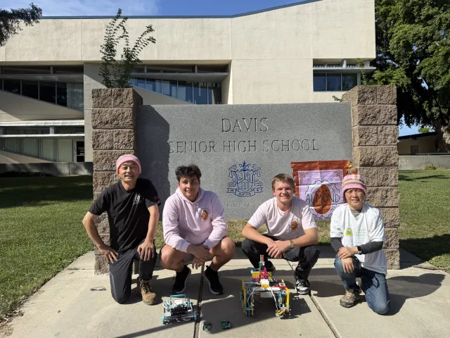 Almond Robotics, Modular Learning, Inc. team crouch by the Davis Senior High School sign