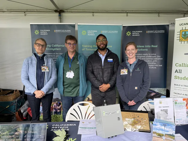 Four people stand in a row in front of California AgTech Alliance and UC ANR banners