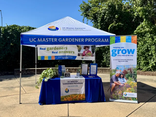 UC Master Gardener Branded Booth set-up with table and pop-up banner