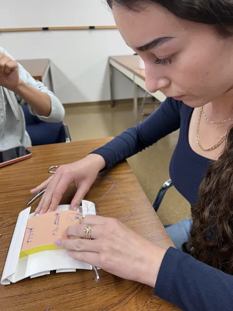 Intern practices suturing pattern on a table