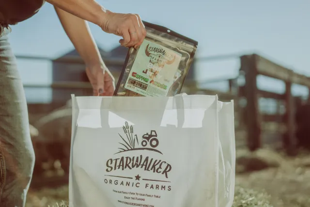 A hand drops a package labeled Starwalker carne asada into a bag labeled Starwalker Organic Farms
