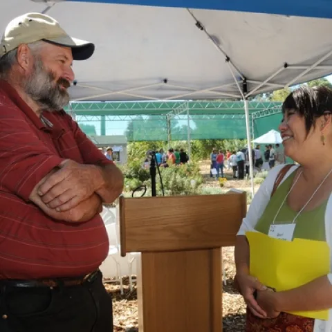 BEEKEEPER Frank Pendell of Pendell Apiaries, Stonyford, Calif., vice president of the California State Beekeepers' Association, chats with Dori Sera Bailey, director of consumer communications, Häagen-Dazs and Dreyer’s Grand Ice Cream. In the back are visitors touring the garden. (Photo by Kathy Keatley Garvey)
