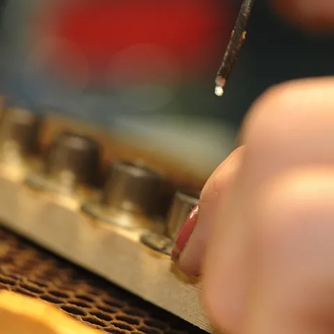 TINY EGG, a future honey bee queen, is moved from a comb to a queen cell cup at the Strachan Apiaries in Yuba City. (Photo by Kathy Keatley Garvey)