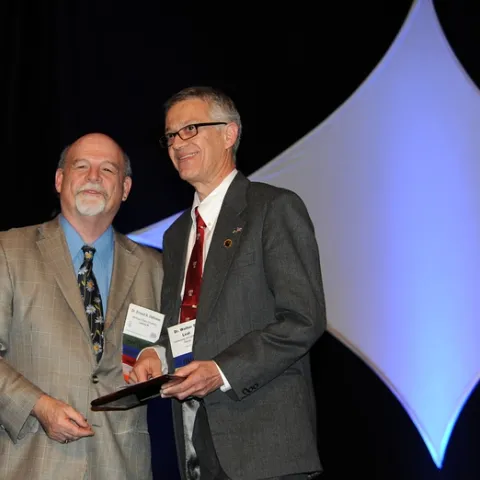 UC Davis pofessor Walter Leal (right) receives the Nan-Yao Su Award from ESA President Ernest Delfosse. (Photo by Kathy Keatley Garvey