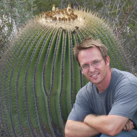 Alex Van Dam, photographed next to a giant cactus.
