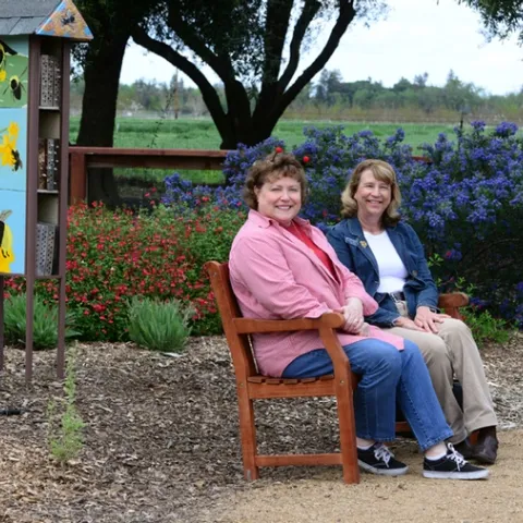 Debra Jamison (left), state regent, and Gayle Mooney, state treasurer, share a bench that the California State Society of the Daughters of the American Revolution purchased for the UC Davis bee garden.