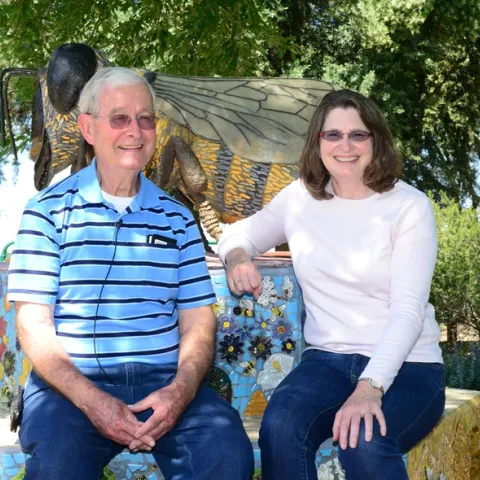 Norm Gary, emeritus professor of entomology at UC Davis who recently retired as a professional bee wrangler, talks bees with Barbara Allen-Diaz, UC ANR vice president. The bee sculpture, in the Häagen-Dazs Honey Bee Haven on Bee Biology Road, UC Davis, is the work of Donna Billick. (Photo by Kathy Keatley Garvey)