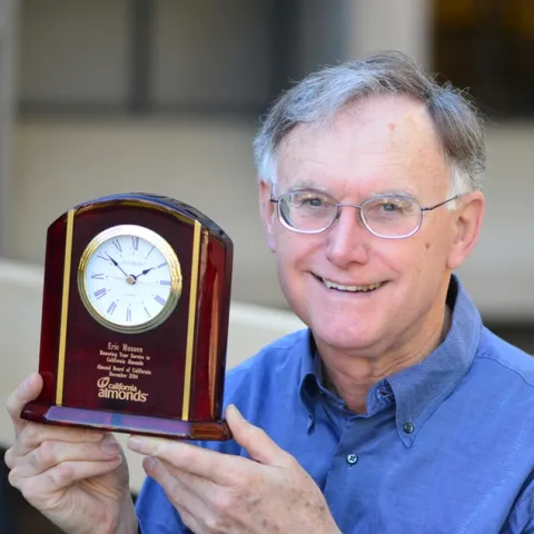 Extension apiculturist (emeritus) Eric Mussen with his engraved clock from the Almond Board of California. (Photo by Kathy Keatley Garvey)