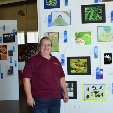 McCormack Hall assistant superintendent Sharon Payne of Vallejo, a past president of the Solano County 4-H Leaders' Council, stands next to youth photography featuring insects. (Photo by Kathy Keatley Garvey)