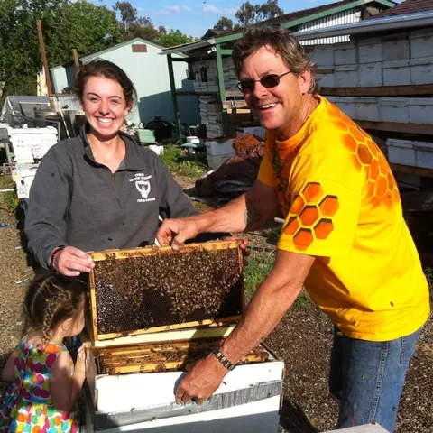 Beekeeper Brian Fishback helping Sheridan Miller with her hive. (Photo by Craig Miller)