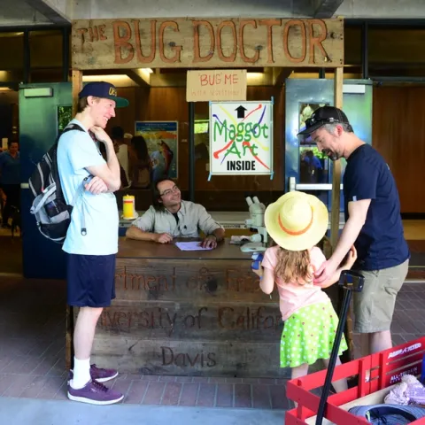Bug Doctor Brendon Boudinot answers a question from Lilliana Phillips, 5, of Carmichael, as her father, William Phillips, watches. (Photo by Kathy Keatley Garvey)
