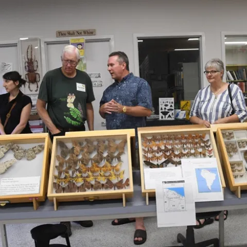Retired entomologist and UC DAvis alumnus Norm Smith (second from left) talks to visitors at the Bohart Museum of Entomology's "Moth Night." The white witch (see display on the far left) is the largest moth in the world. (Photo by Kathy Keatley Garvey)